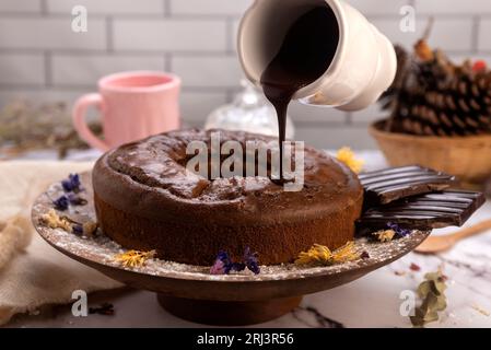 Il budino di cioccolata calda fuso viene versato su una torta al cioccolato come glassa Foto Stock