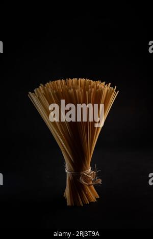Una vista ravvicinata dei noodle crudi legati con una corda su una superficie nera Foto Stock