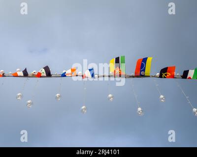 Molte piccole bandiere di stato. Bandiere del festival. Paesi del mondo. Stemmi e bandiere contro il cielo. Concetto di viaggio Foto Stock