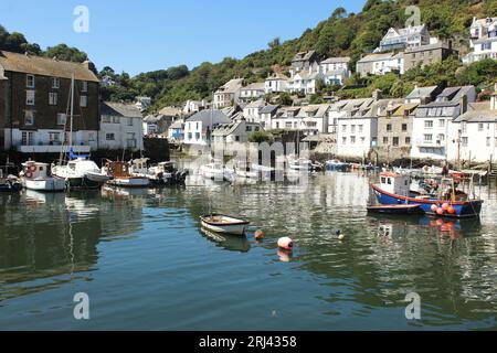 Una scena idilliaca con diverse piccole barche attraccate nelle tranquille acque di un porto, con edifici pittoreschi sullo sfondo Foto Stock