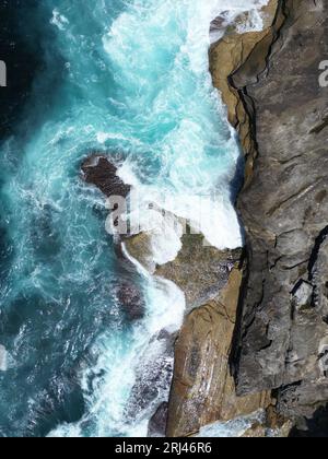 Una vista aerea delle onde del mare che si infrangono sulla costa rocciosa Foto Stock