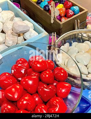 Un primo piano di una varietà di rocce a forma di cuore contenute in ciotole e scatole decorate Foto Stock