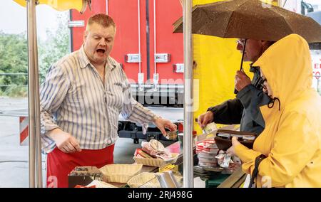 Amburgo, Germania. 23 luglio 2023. Axel Pabst vende formaggio al mercato del pesce di Amburgo. Da più di 25 anni Axel Pabst lavora come market crier per l'azienda Fred4Food, che è diventata nota nel mercato del pesce attraverso il commercio di frutta Bananen-Fred. Nel frattempo, però, non c'è più solo frutta nell'assortimento, ma anche, tra le altre cose, il proprio stand di formaggi. Meglio conosciuto come: Cheese-Fred. (A dpa: "Gridare per Käse-Fred - un venditore di pesce in missione") credito: Markus Scholz/dpa/Alamy Live News Foto Stock