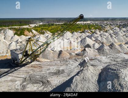 Il dragline a piedi con paranco e benna lavora in cava di pietra Foto Stock