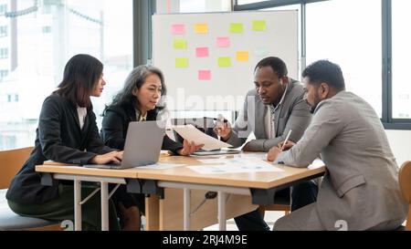 Un gruppo multirazziale di uomini d'affari è in riunione per fare un brainstorming e consultarsi insieme su un nuovo piano di investimento aziendale nella sala riunioni. div Foto Stock