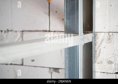 Primo piano di un profilato metallico per una parete. Divisorio in fase di costruzione. Collegamento mediante viti autofilettanti con un trapano. Nervature di irrigidimento in A. Foto Stock