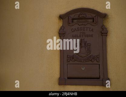 Antichissima cassetta postale in ghisa su un muro in stucco ocra a Scicli, Sicilia. Foto Stock