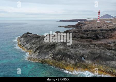 Vista aerea di un faro situato su una scogliera rocciosa che si affaccia su un grande specchio d'acqua Foto Stock