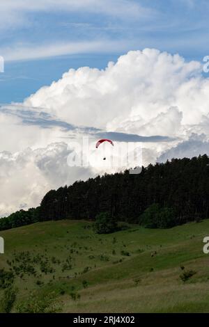 Parapendio volare sulle montagne nel giorno di estate Foto Stock