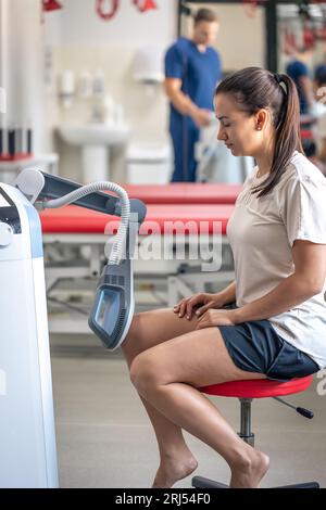 Medico che utilizza la macchina per trattare le articolazioni del ginocchio di un paziente. Foto Stock