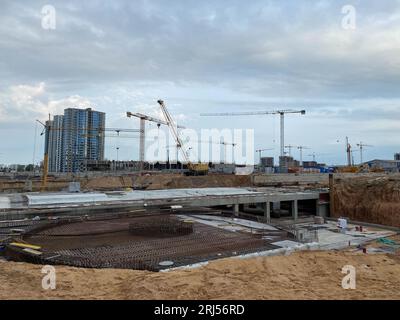 Costruzione di una grande struttura industriale di infrastrutture sotterranee con una fondazione che utilizza potenti gru da costruzione. Foto Stock