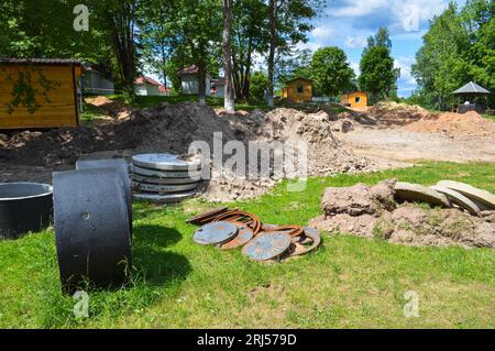 Grandi anelli tondi in cemento cementizio per la costruzione di pozzi di liquame durante la costruzione della casa. Foto Stock