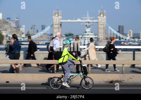 Una donna sta guidando una bicicletta elettrica Brompton pieghevole attraverso il London Bridge, Londra, Regno Unito. 7 giugno 2023 Foto Stock