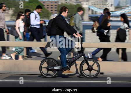 Un uomo in sella a una bicicletta elettrica pieghevole Gocycle durante l'ora di punta serale attraverso il London Bridge, Londra, Regno Unito. 7 giugno 2023 Foto Stock