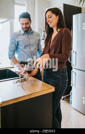 Una coppia amorevole in cucina. Una giovane donna apre una bottiglia di vino Foto Stock