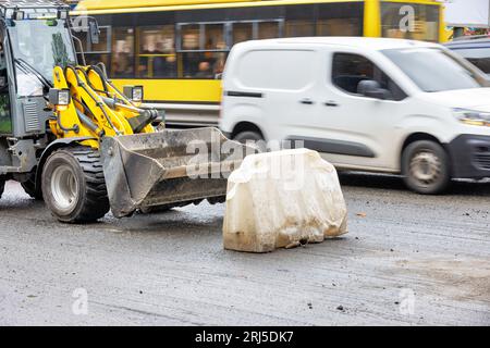 Un trattore stradale è parcheggiato sul bordo della strada sullo sfondo del trasporto urbano. Foto Stock