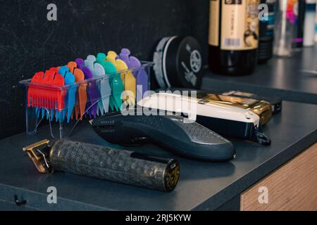 Una selezione di rifinitori per capelli su un bancone in un barbiere accanto ad altri prodotti per la cura dei capelli Foto Stock