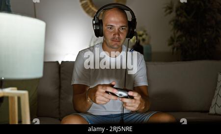 Giovane ispanico che gioca video gioco seduto sul divano a casa Foto Stock