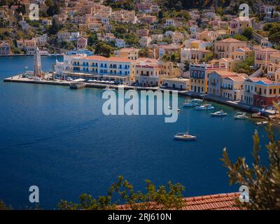 Isola di Symi, Grecia. Vacanze nelle isole della Grecia da Rodi nel Mar Egeo. Case colorate in stile neoclassico nella baia di Symi. Informazioni generali sui viaggi di vacanza. vista dalla collina Foto Stock