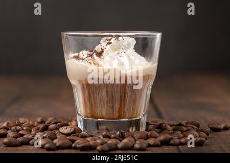 Espresso caldo con panna in tazza di vetro su un tavolo di legno Foto Stock