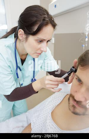 medico che inserisce l'apparecchio acustico nell'orecchio di mans Foto Stock