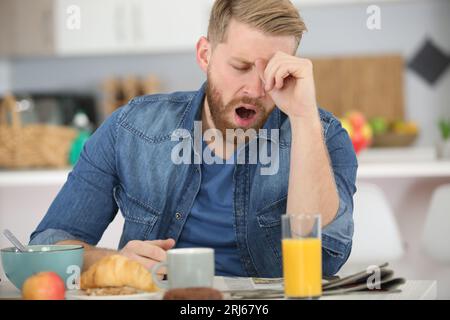 Uomo di addormentarsi durante la sua colazione dopo il lavoro straordinario Foto Stock