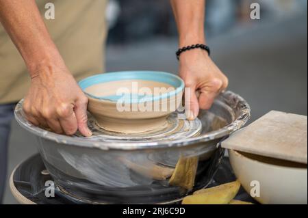 Donna potter che prende il piatto finito dalla ruota in ceramica, che fa terracotta. Foto Stock
