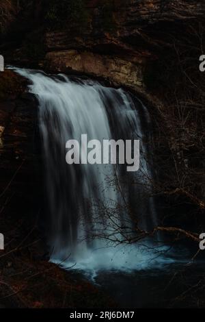 Una potente e maestosa cascata scende lungo il fianco di una montagna rocciosa, creando una bella e pittoresca scena Foto Stock