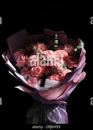 Un bouquet vibrante di garofani rosa e bianco e rose disposti su un colore nero Foto Stock