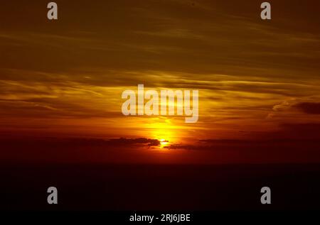 Un vivace cielo nuvoloso al tramonto nelle sfumature di giallo e rosso. Foto Stock