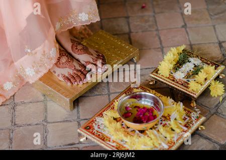 Un primo piano dei piedi di una sposa indiana con l'henné in cima a una superficie dorata Foto Stock