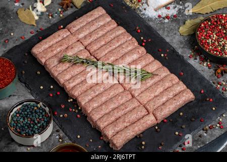 Polpettine di manzo crude. Polpette di manzo crude fresche su sfondo scuro. Macelleria. Nome locale inegol kofte Foto Stock