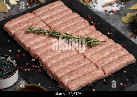 Polpettine di manzo crude. Polpette di manzo crude fresche su sfondo scuro. Macelleria. Nome locale inegol kofte. Primo piano Foto Stock