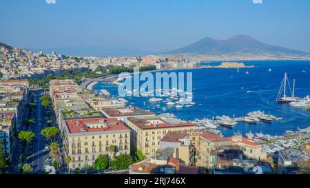 Una vista aerea del vibrante paesaggio urbano costiero con l'oceano blu e le barche a vela bianche in primo piano Foto Stock