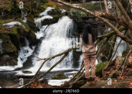 Una donna che fotografa una cascata all'interno della Enders State Forest a Granby, Connecticut, in una giornata invernale. Foto Stock