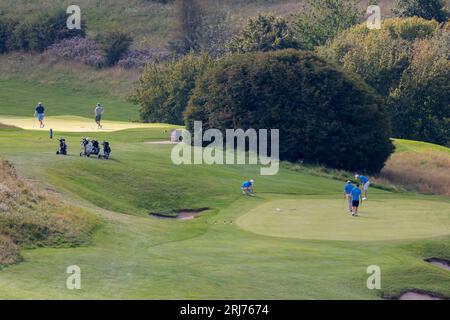 Campo da golf con green e bunker, mazze da golf, borse, trolly e sei golfisti immergono le colline della valle, i cespugli e gli alberi prelevati dall'alto sull'anello cissbury Foto Stock