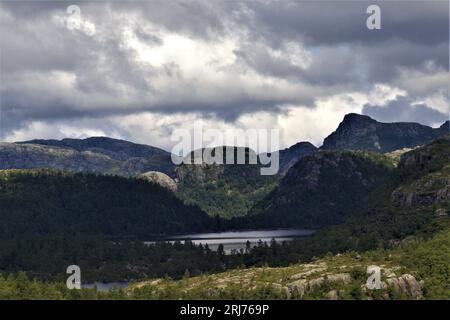 Immersa nella tranquilla escursione di Stavanger: Un tranquillo lago di montagna incorniciato da alberi e cime monumentali in pietra. La grandezza della natura in Norvegia. #MountainHike Foto Stock