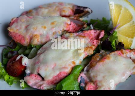 cozze cotte al forno con caviale masago e formaggio su un piatto bianco con limone Foto Stock