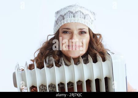 Ciao inverno. donna sorridente alla moda con maglione, guanti, cappello e sciarpa isolati su sfondo bianco con riscaldatore. Foto Stock