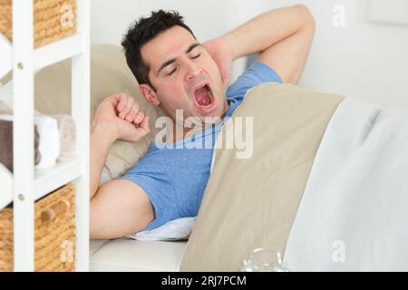 un uomo sbadiglia a letto Foto Stock