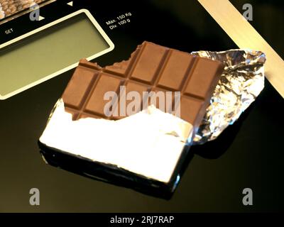 barretta di cioccolato su scala elettronica, foto concettuale Foto Stock