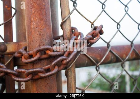 Cancello bloccato da una grande catena arrugginita. Concetto di sicurezza e protezione. Foto Stock