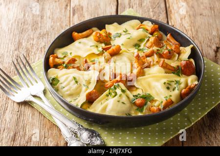 Porzione di triangoli di pasta ripiena di funghi, cipolle ed erbe da vicino in un piatto sul tavolo. Orizzontale Foto Stock