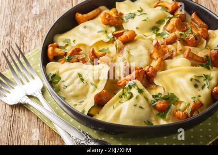 Pasta italiana a forma di triangolo ripiena di funghi, cipolle ed erbe da vicino in un piatto sul tavolo. Orizzontale Foto Stock