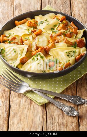 Triangoli triangolari di pasta italiana con funghi chanterelle, cipolla ed erbe da vicino in un piatto sul tavolo. Verticale Foto Stock