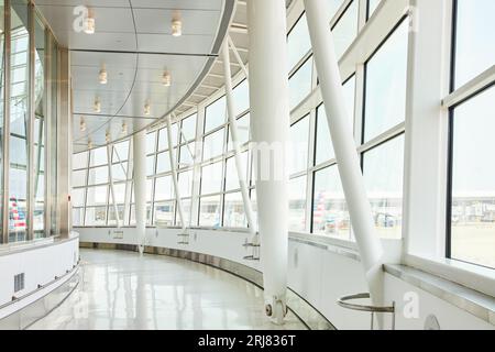 Vista interna dei corridoi curvi con finestre che si affacciano sull'esterno dell'aeroporto Foto Stock