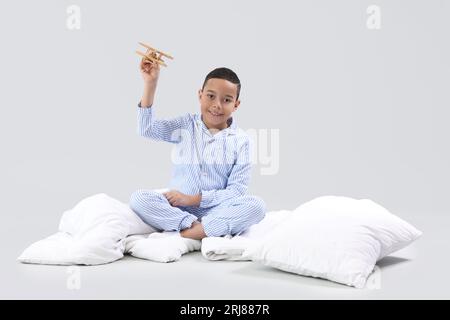 Ragazzino afroamericano con piano in legno e morbida coperta su sfondo chiaro Foto Stock