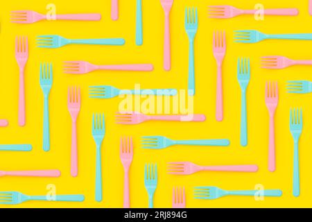 Le forche in plastica rosa e blu sono piatte su sfondo giallo Foto Stock