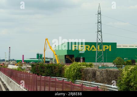 Brescia, Italia - 13 giugno 2023: Edificio di produzione della Feralpi che produce prodotti siderurgici. Vista di un edificio verde con un inscri giallo Foto Stock