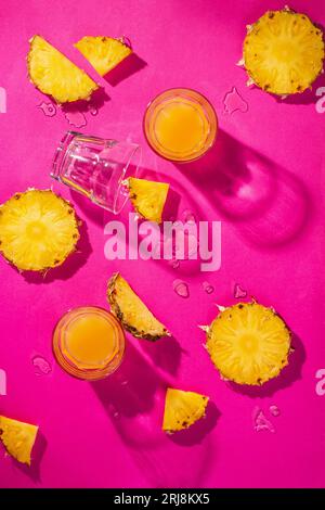 Pezzi di ananas e succo di ananas isolati su sfondo rosa. Concetto di vacanza tropicale. Base piatta, vista dall'alto Foto Stock